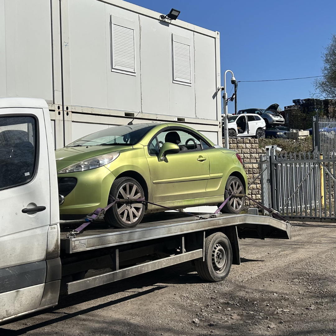 Green convertible on flatbed tow truck