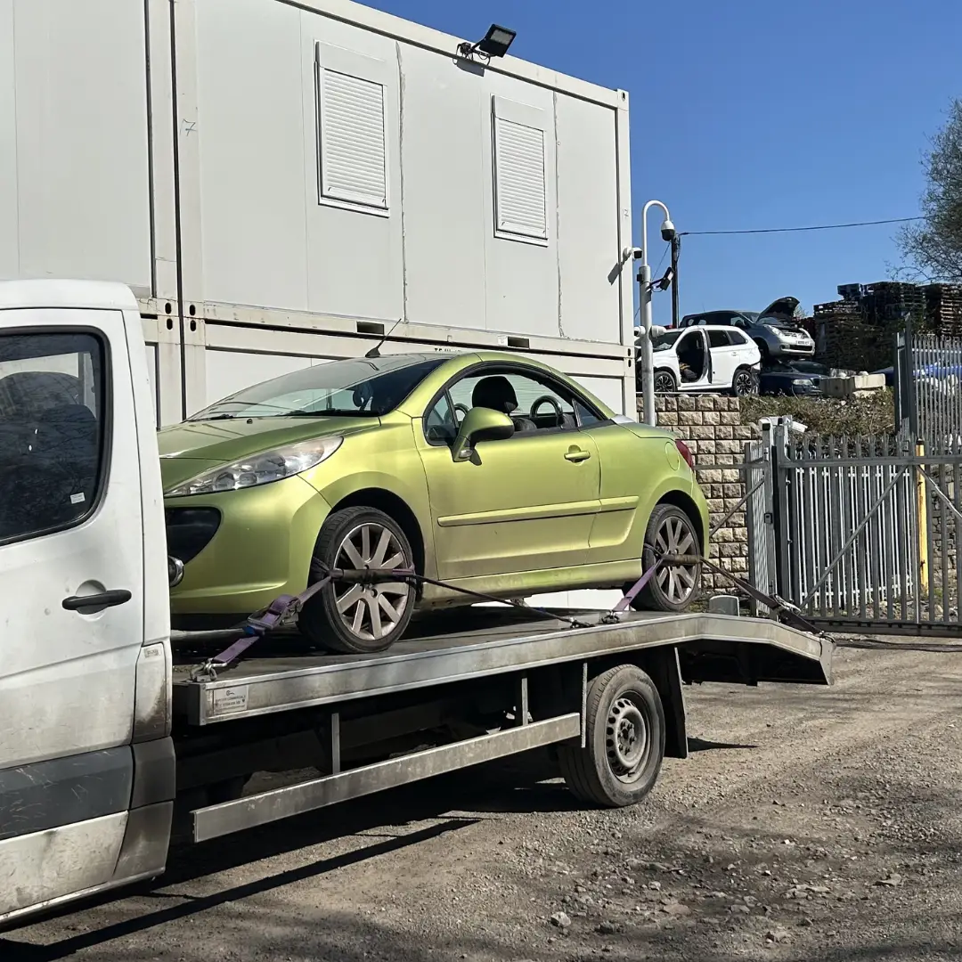 Green convertible on flatbed tow truck