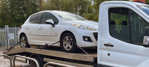 White car secured on flatbed recovery truck