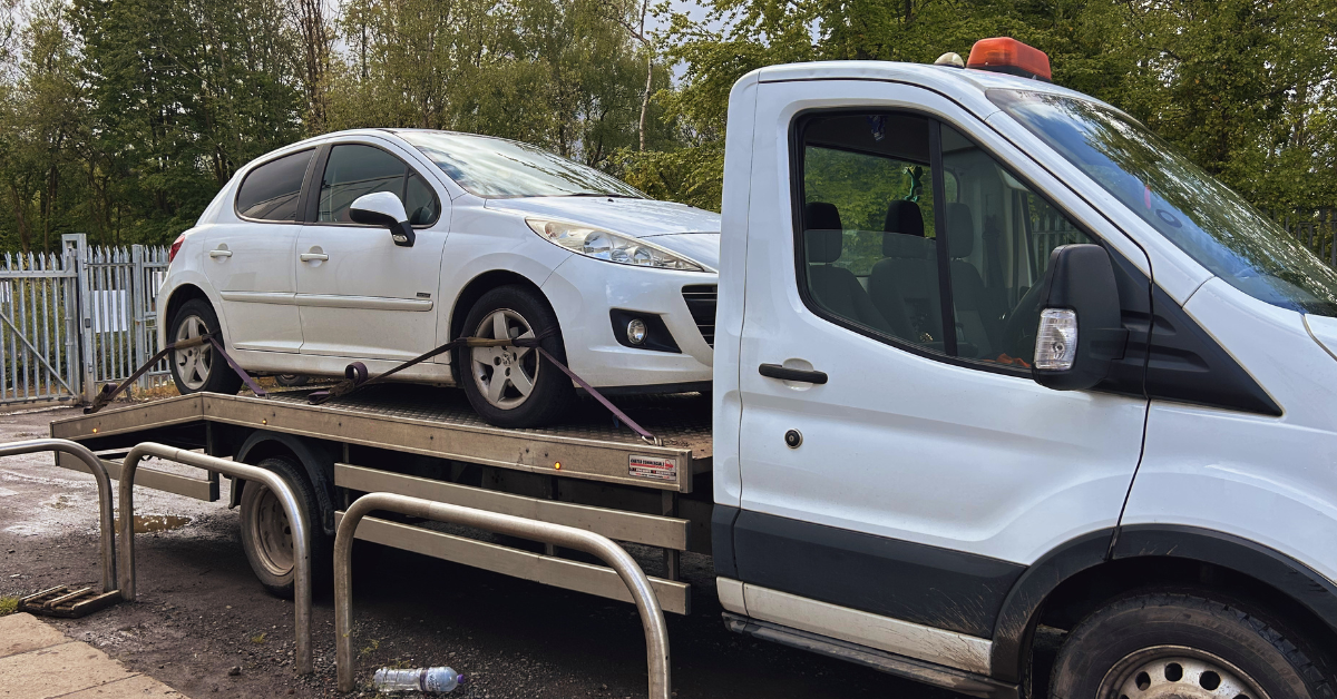 White car secured on flatbed recovery truck