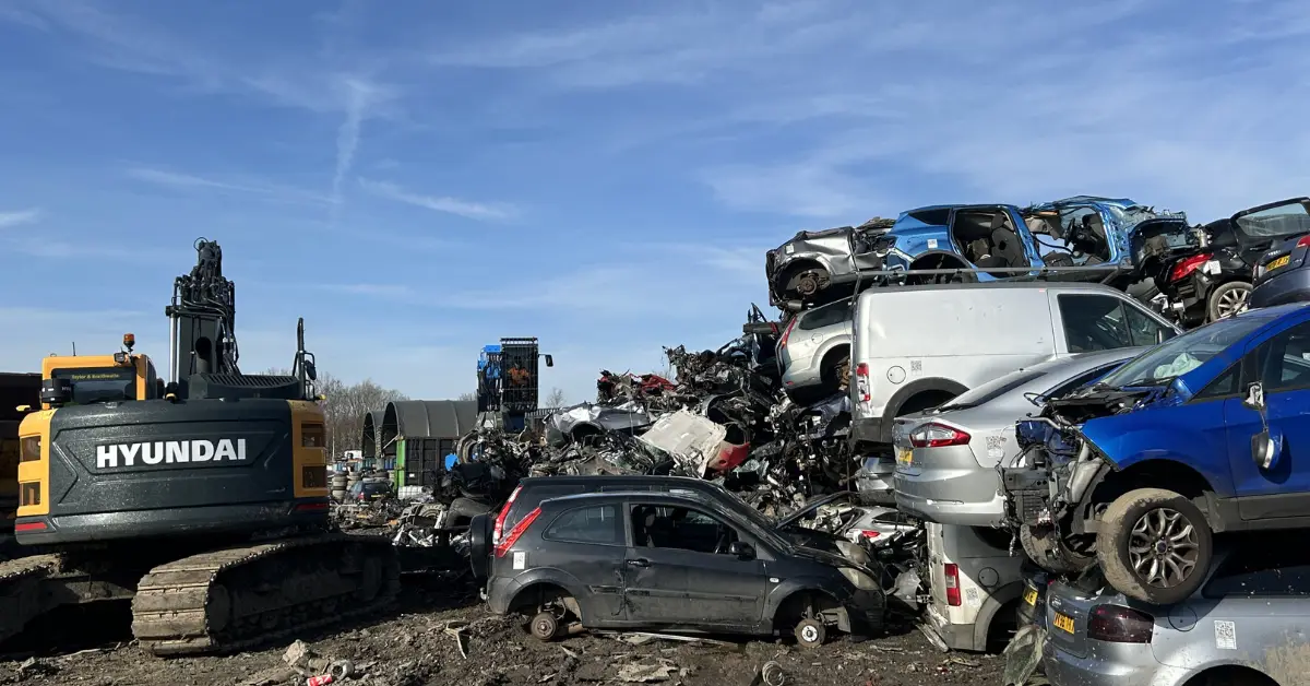Scrapyard with stacked crushed cars and excavator