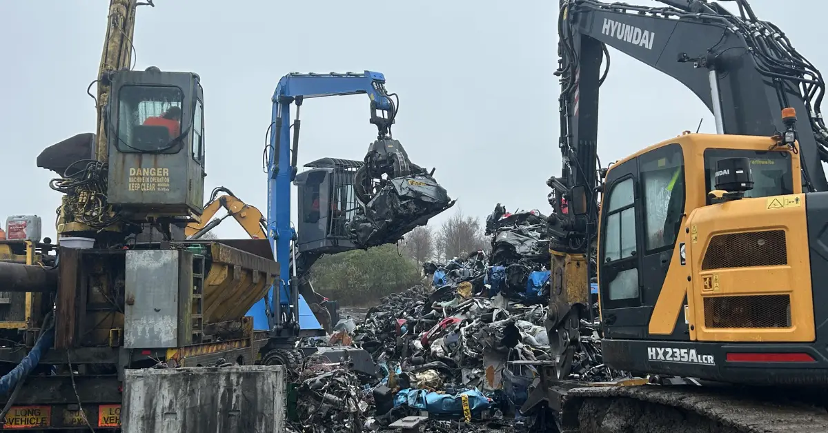 Excavators lifting crushed cars at scrapyard