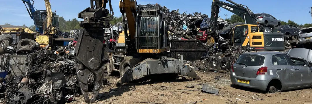 Excavators sorting scrap cars in busy scrapyard