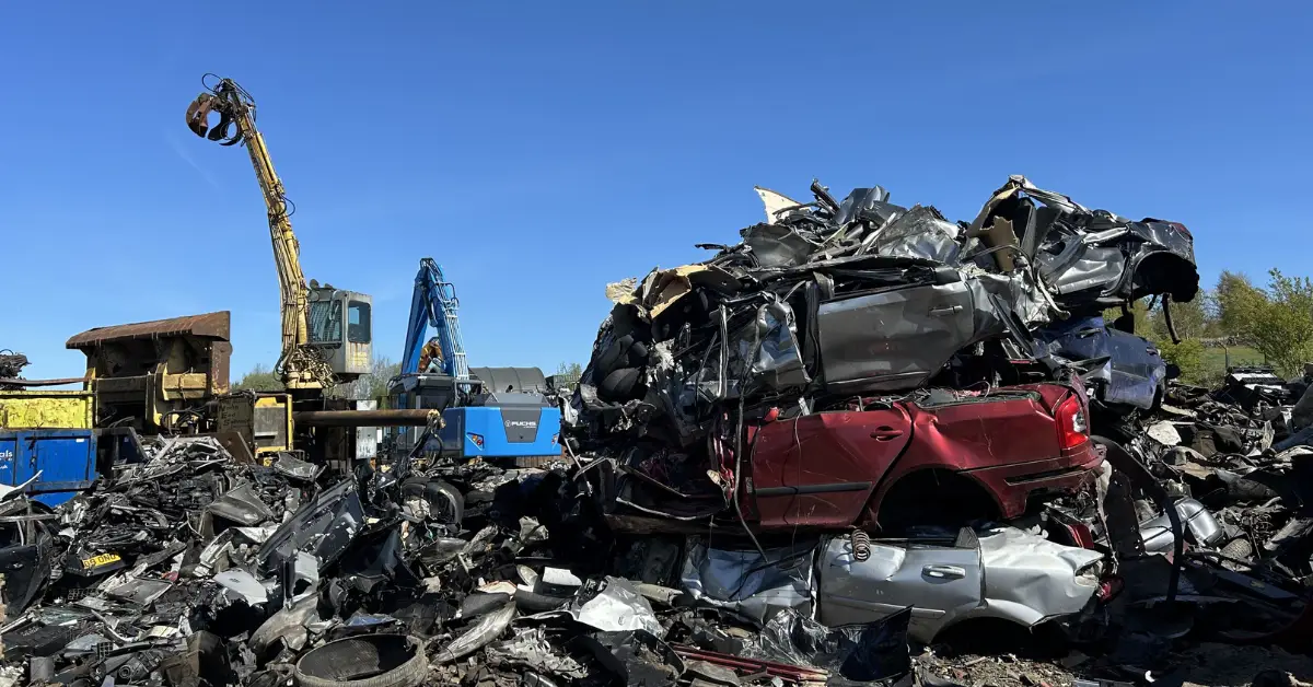 Scrapyard with crushed cars and excavator crane