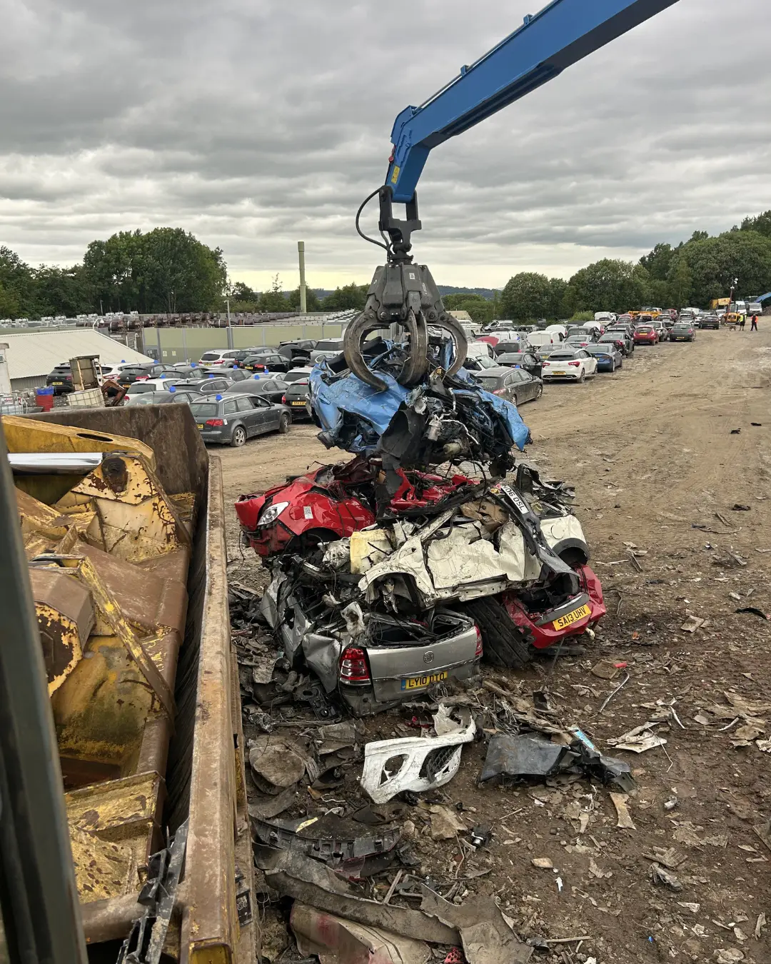 Crane lifting crushed cars in scrapyard