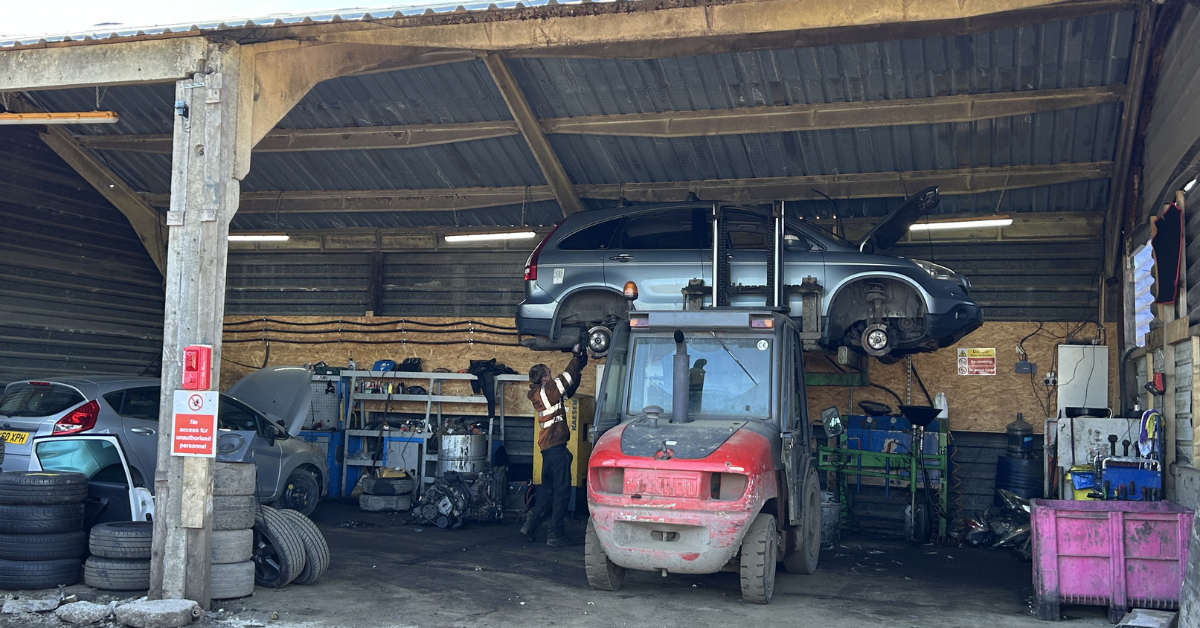 Forklift lifting SUV inside busy garage workshop