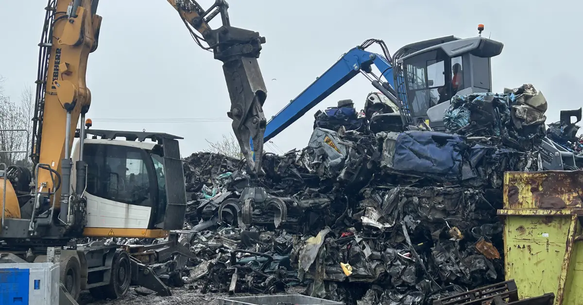 Excavators sorting crushed cars at scrapyard